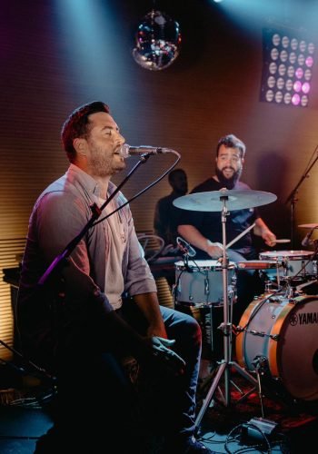 Foto de cantante de la banda con baterista de fondo